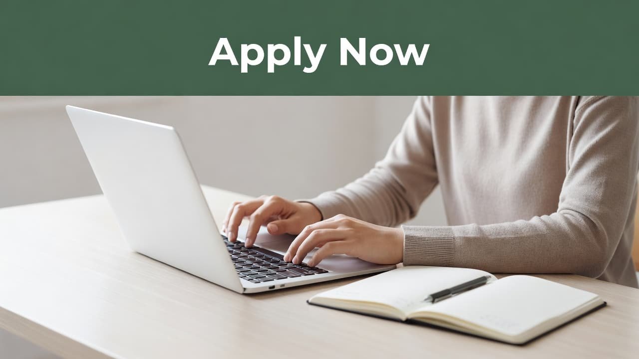 A close-up perspective captures a student typing on a silver laptop keyboard next to an open notebook. A sleek dark-green bar across the top displays the bold white text Apply Now.